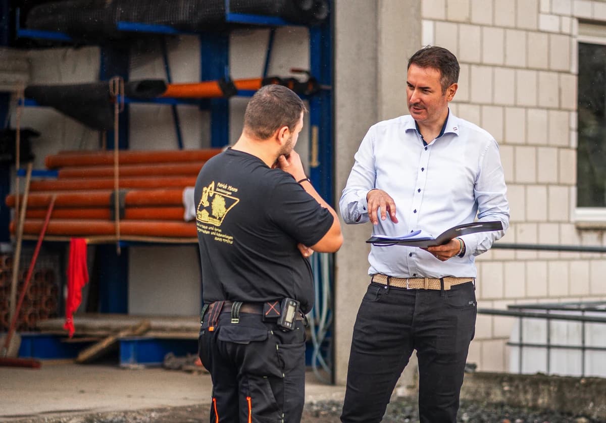Ronny Somieski bespricht Kennzahlen mit einem Handwerker auf dem Betriebsgelände